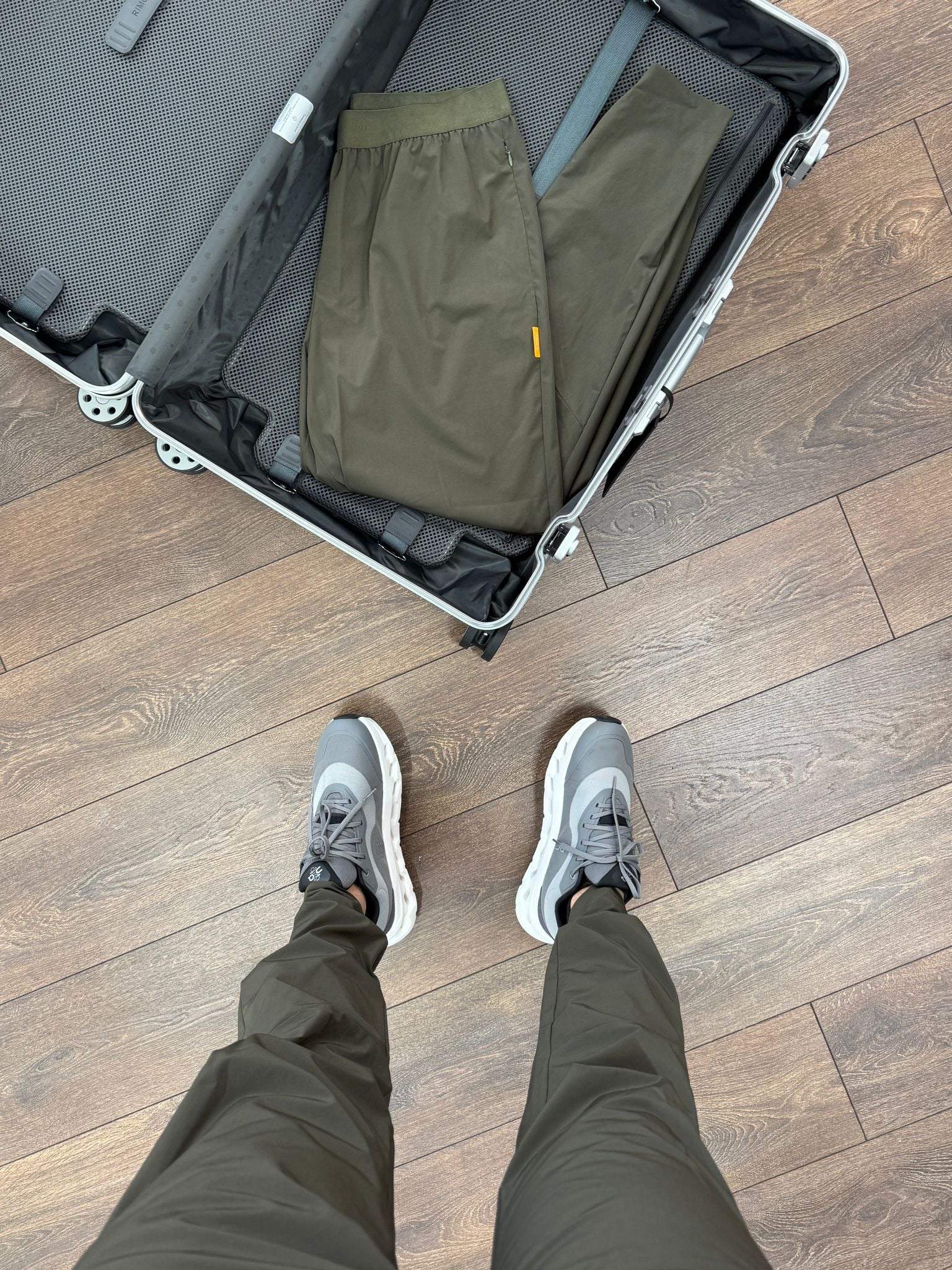 Studio By Charles khaki trackpants packed in suitcase and worn with sneakers on wooden floor
