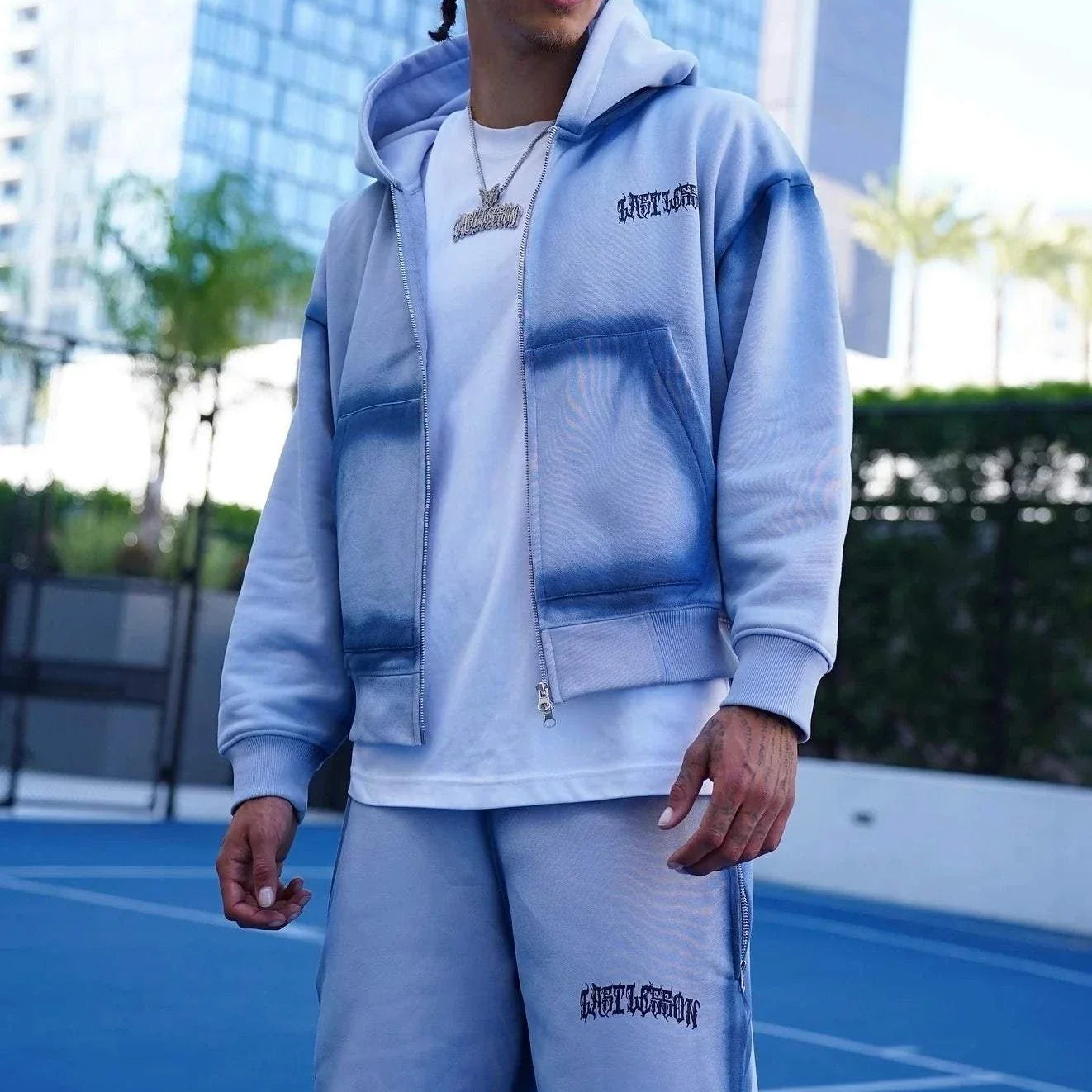 Last Lesson Blue Sprayed Hoodie on model outdoors.