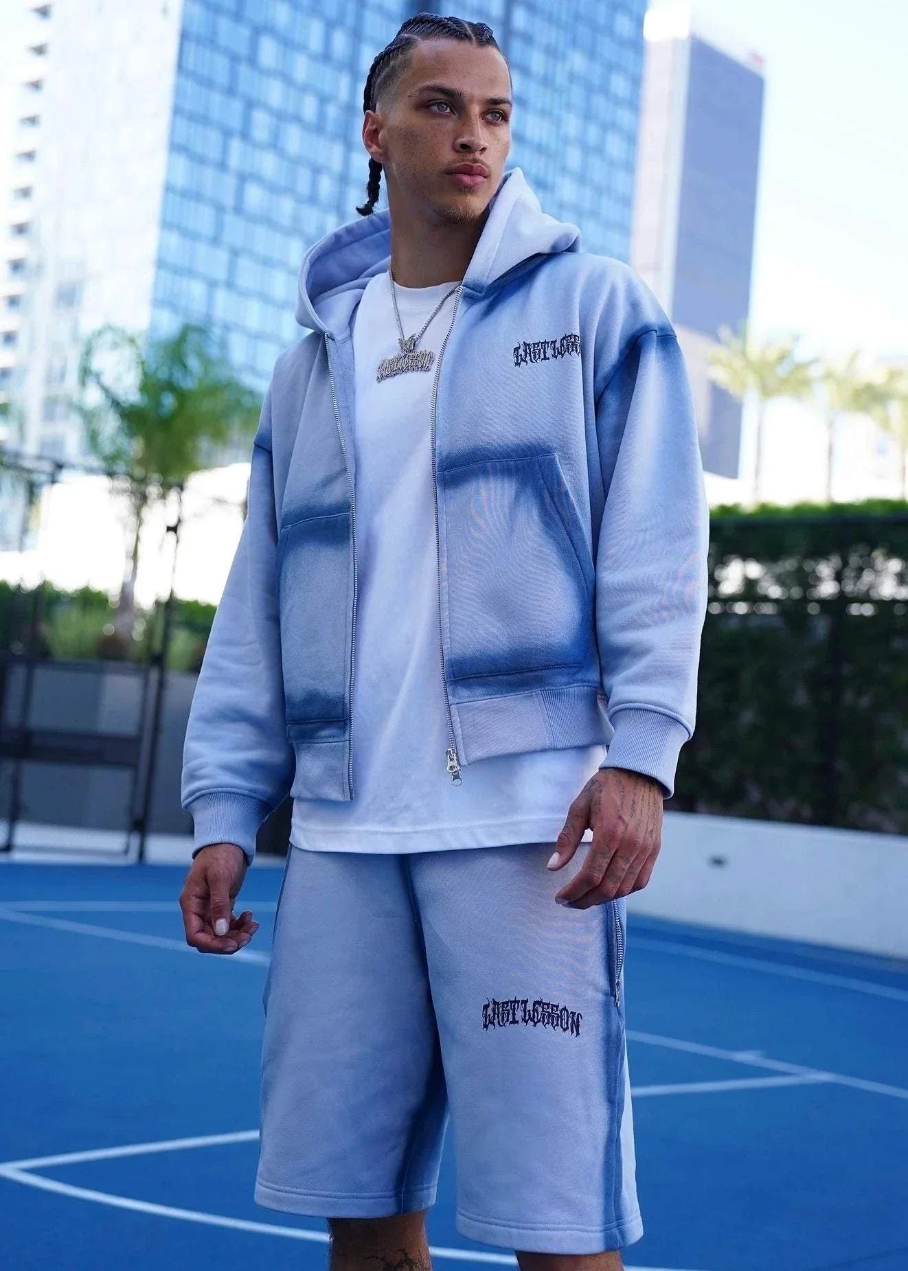 Last Lesson Blue Sprayed Hoodie on model outdoors.