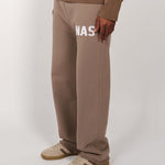 Taupe Natural Art Studio sweatpants with appliqué logo, raw edges, and elastic waistband