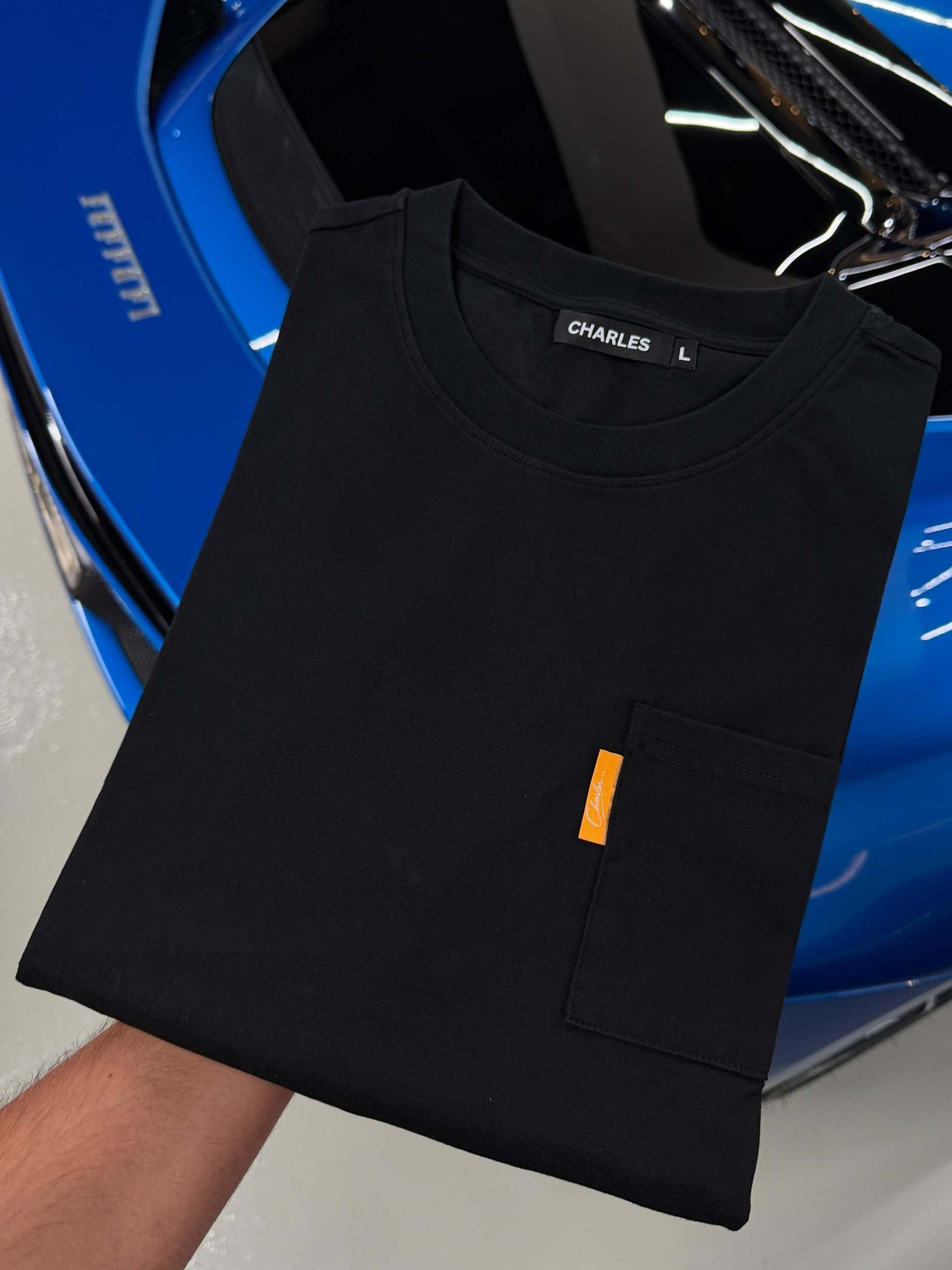 Studio By Charles black long sleeve tee with front pocket folded on blue car hood