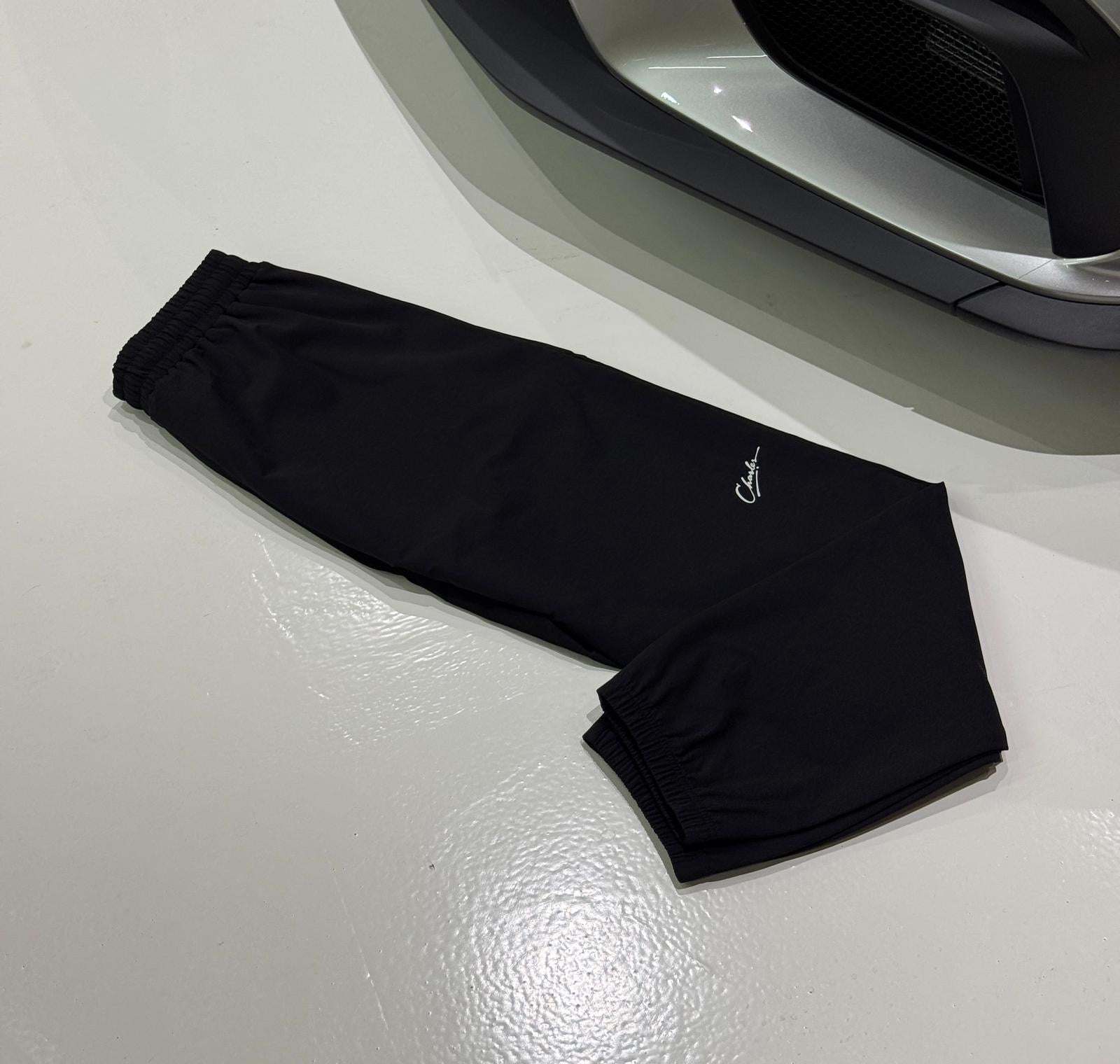 Studio By Charles black Studio Trackpant 2.0 laid flat on white floor near car bumper