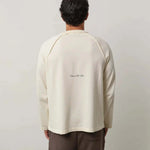 Man wearing Natural Art Studio Raglan long sleeve shirt with inside-out raglan seams and a boxy fit, shown from the back