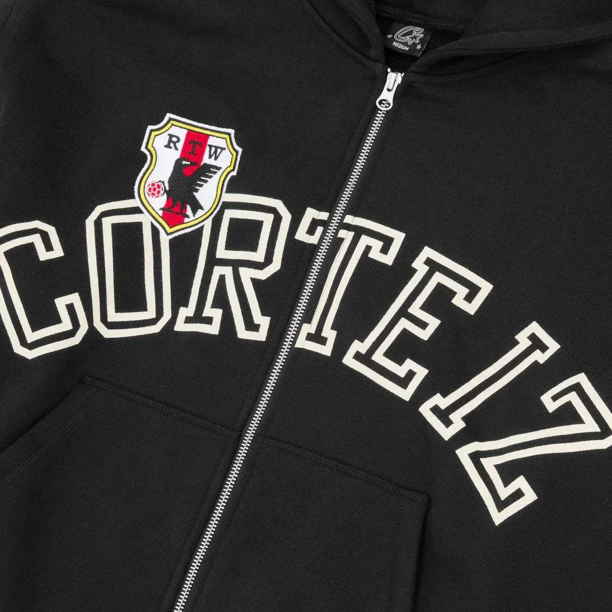 Black Corteiz Arch Shield zip hoodie with crest and bold lettering