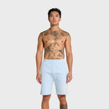 Man wearing ANNIE HOOD baby blue college shorts standing against white background