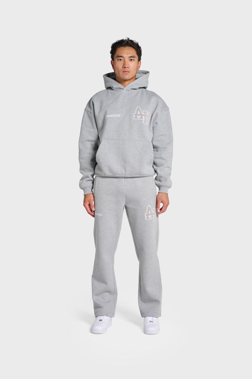 Model wearing grey ANNIE HOOD College Hoody with dropped shoulder and double embroidery logo, paired with matching joggers