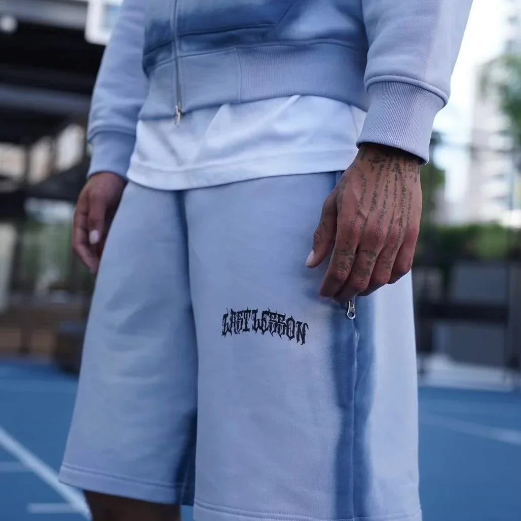 Last Lesson Blue Sprayed Shorts worn outdoors.