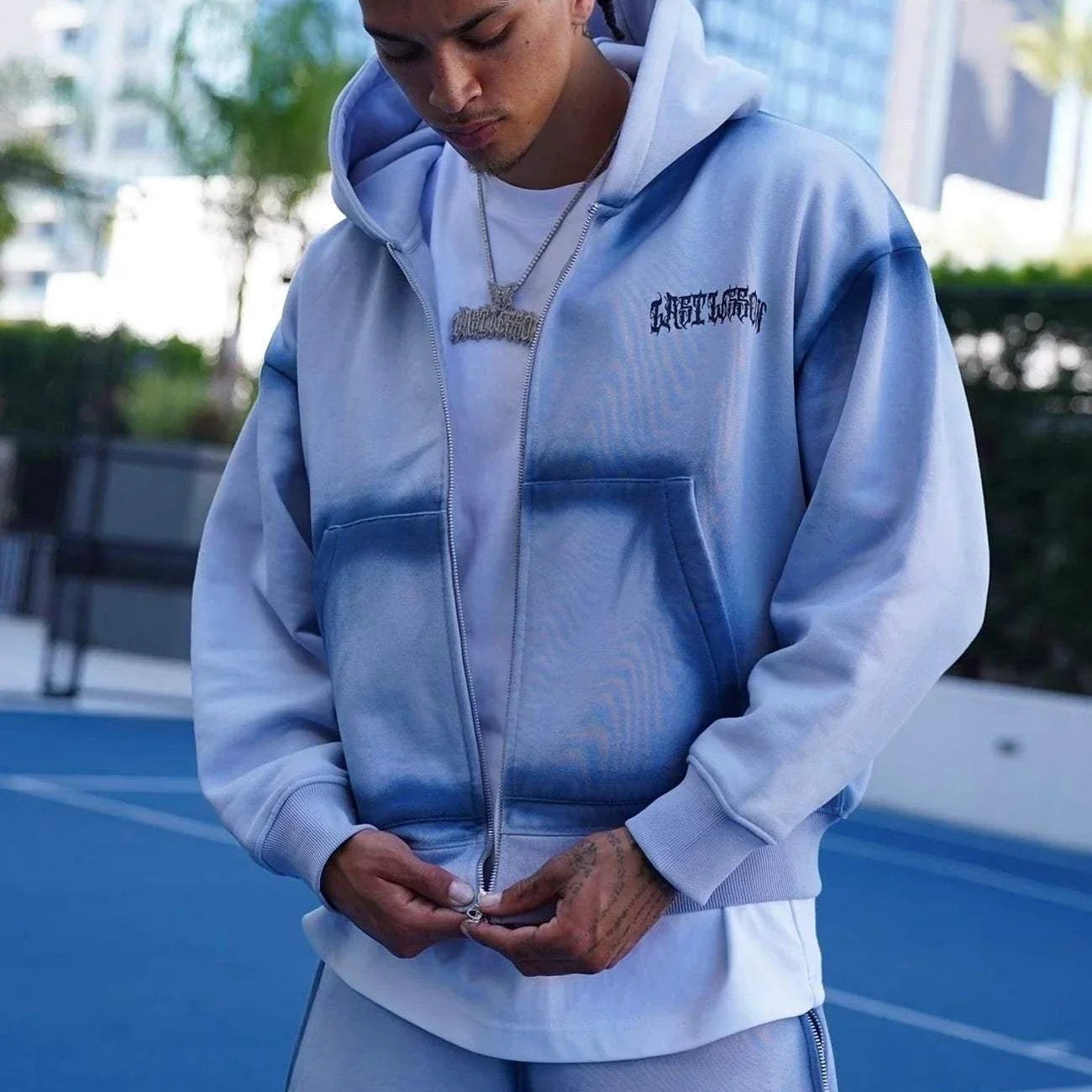 Last Lesson Blue Sprayed Hoodie on a person outdoors.