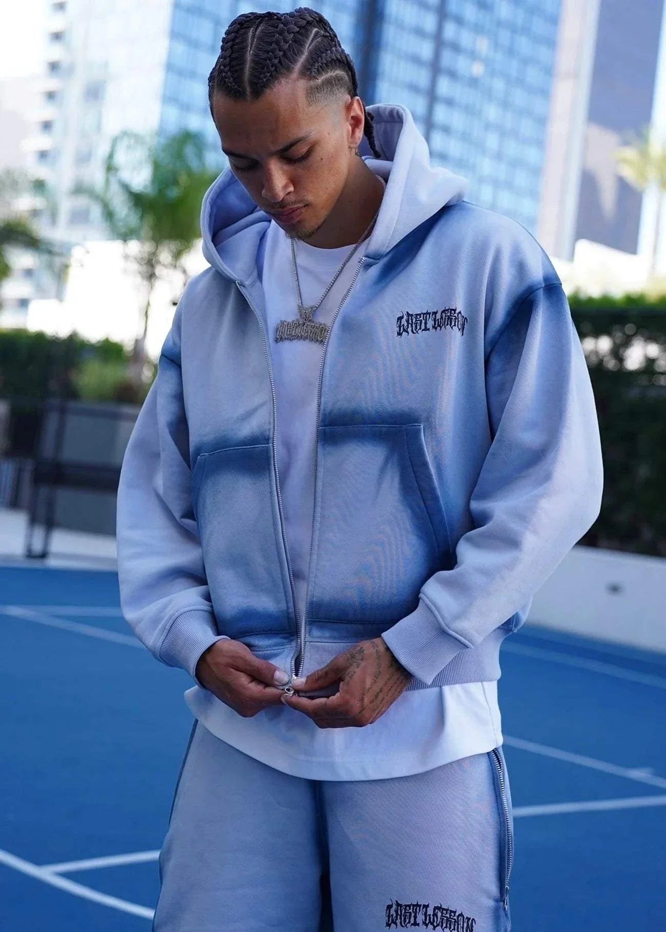 Last Lesson Blue Sprayed Hoodie on a person outdoors.