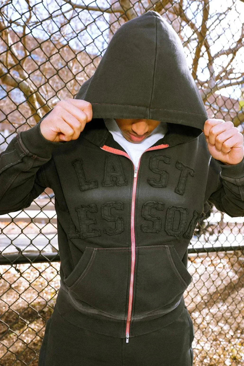 Last Lesson Appliqué Black Hoodie worn by a model outdoors.