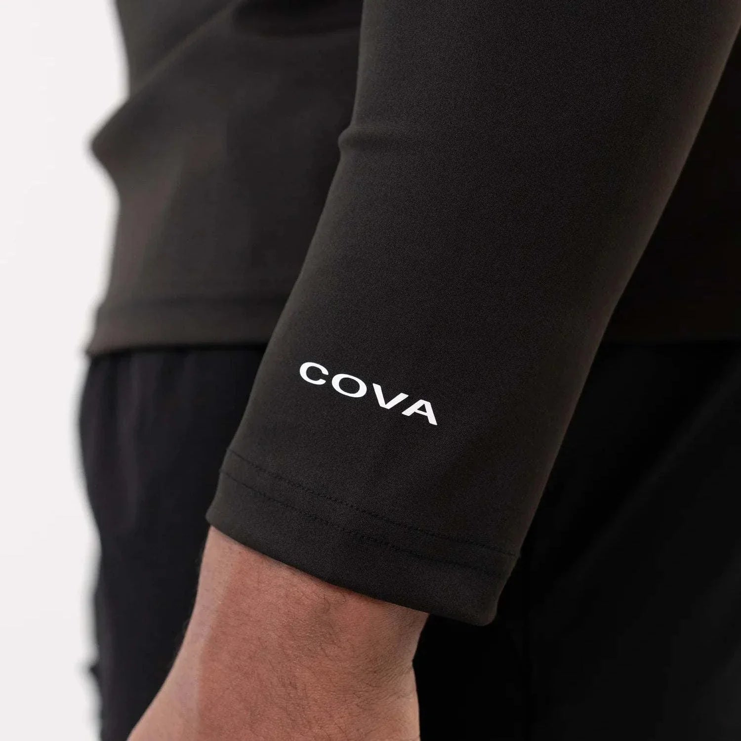 Close-up of black Cova Daily quarter zip sleeve with COVA logo