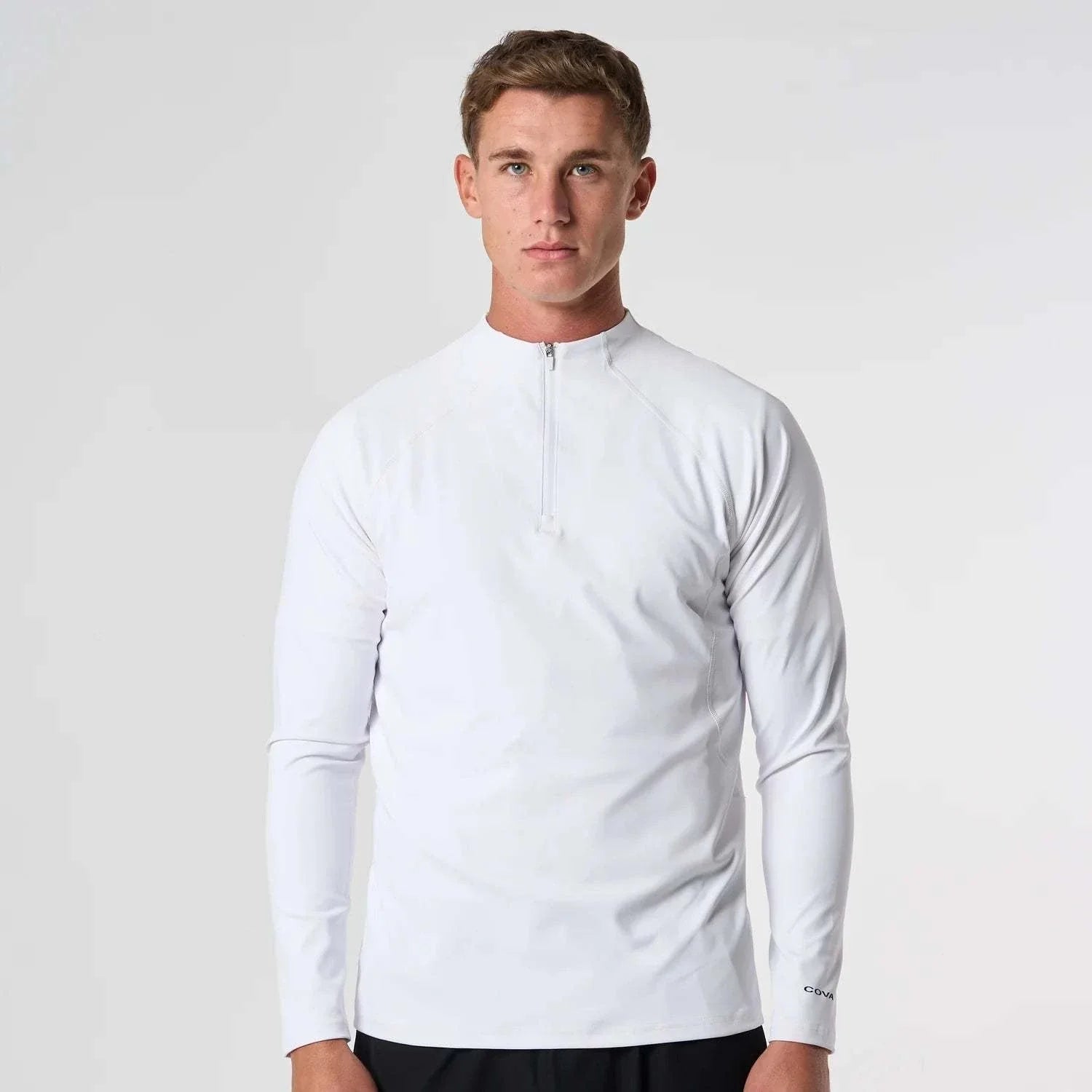 Male model wearing white Cova Daily Quarter Zip with long sleeves and front zipper