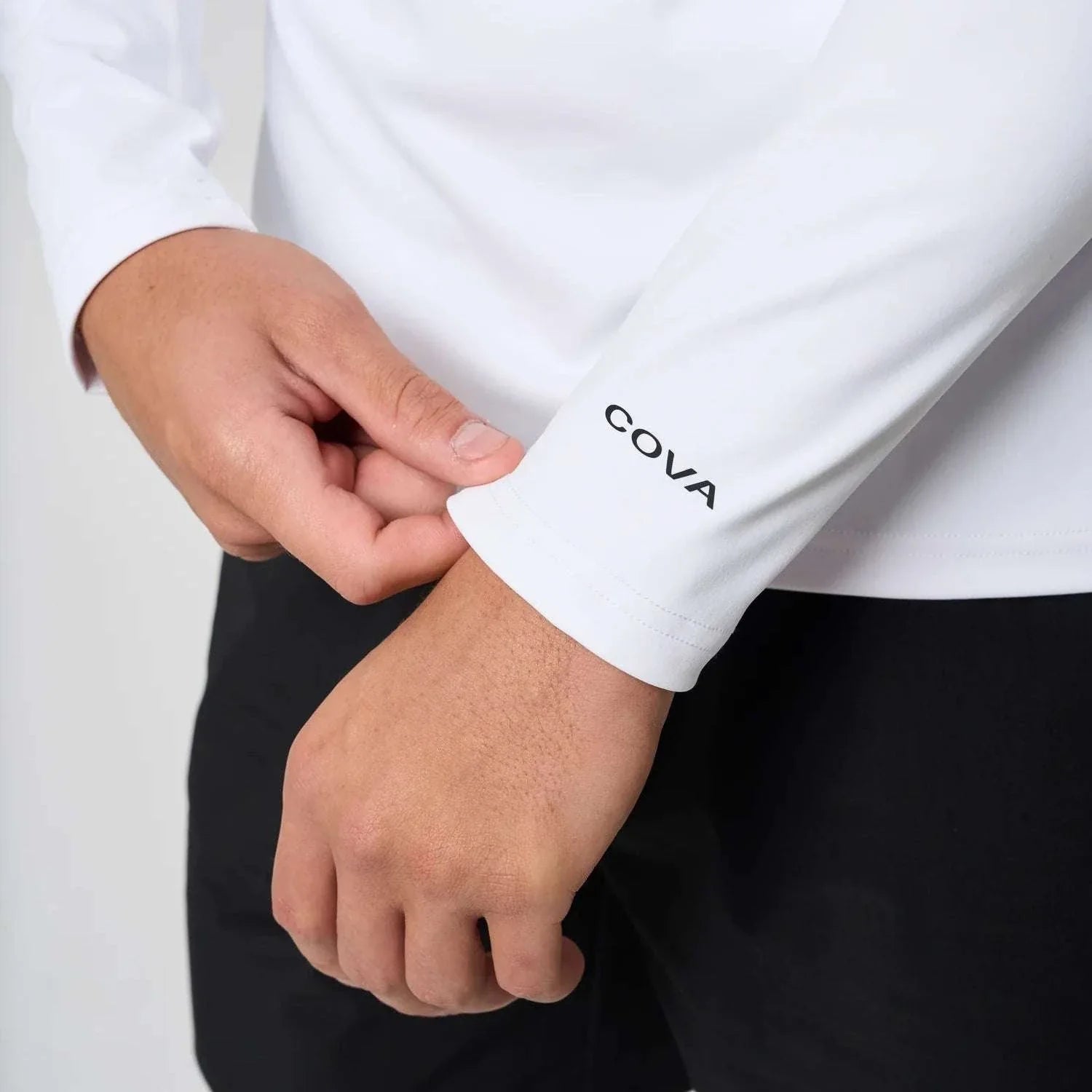 Close-up of Cova Daily Quarter Zip white long sleeve with logo on cuff