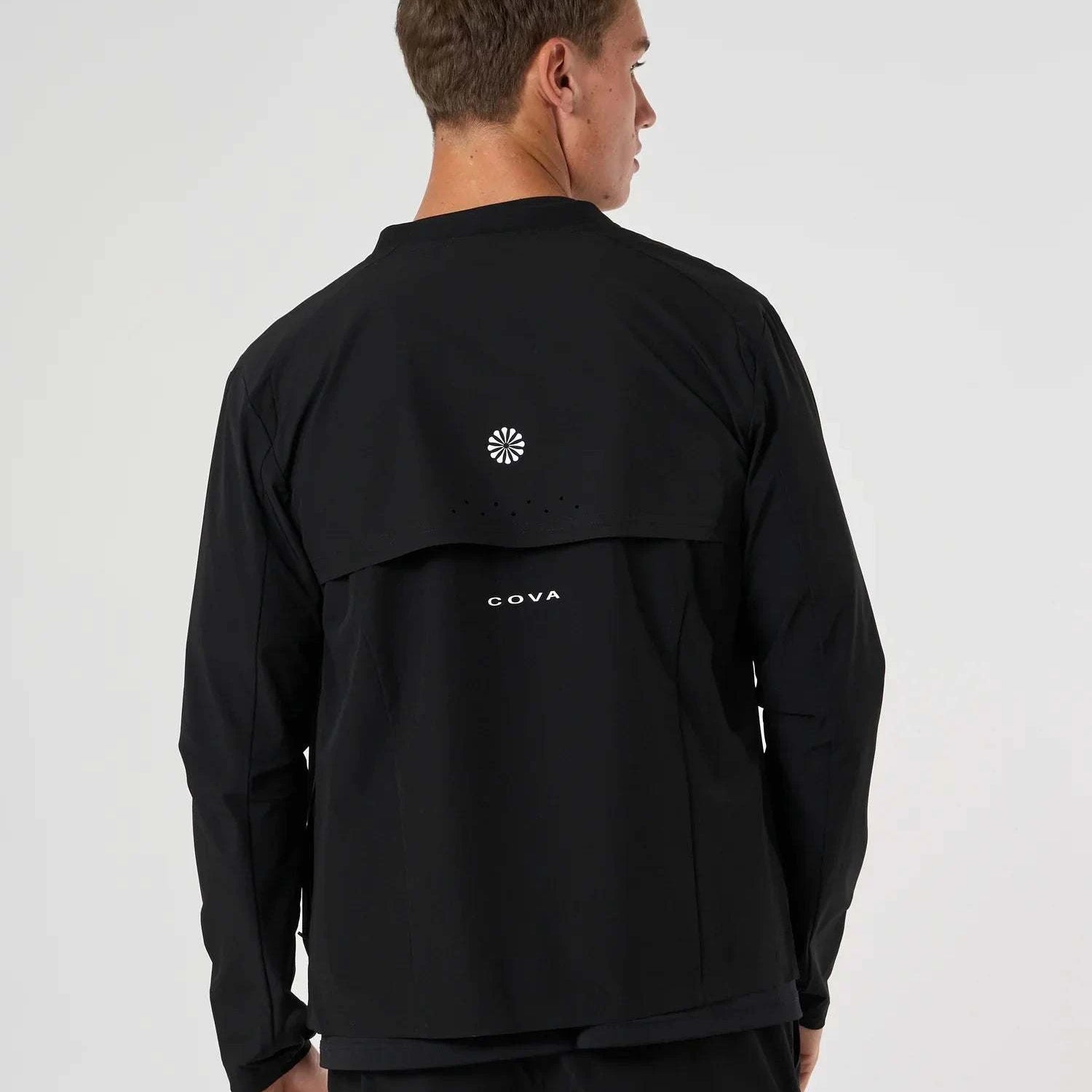 Back view of man wearing black Cova Daily Track Jacket with logo
