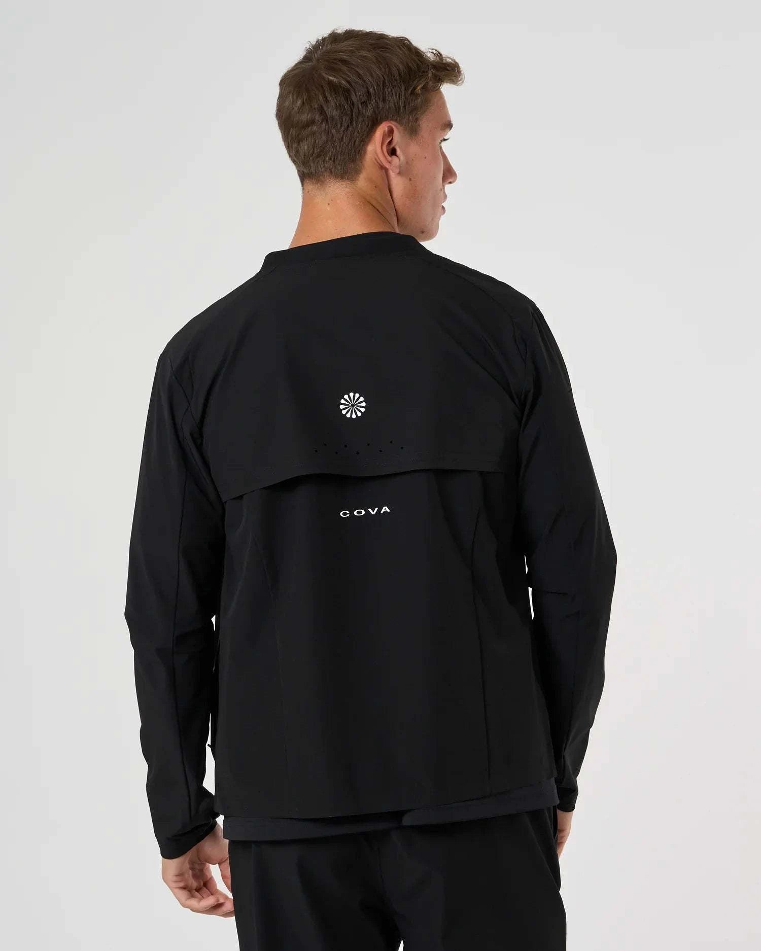 Back view of man wearing black Cova Daily Track Jacket with logo