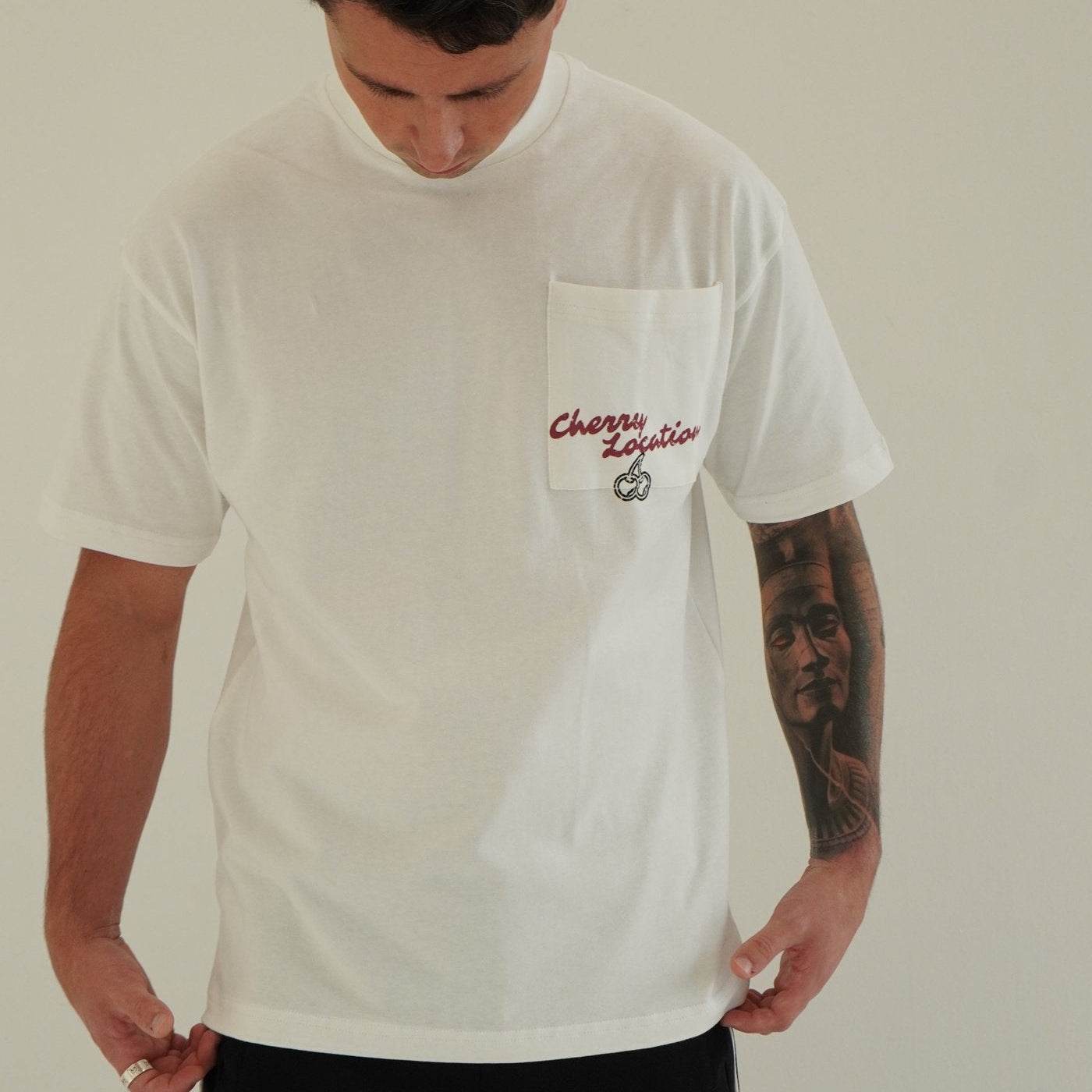 White Cherry Location T-Shirt with chest pocket and red embroidered logo worn by man with tattooed arm