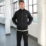 Man wearing Cherry Location black tracksuit with zipper in indoor setting