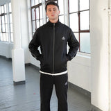 Man wearing Cherry Location black tracksuit with zipper in indoor setting