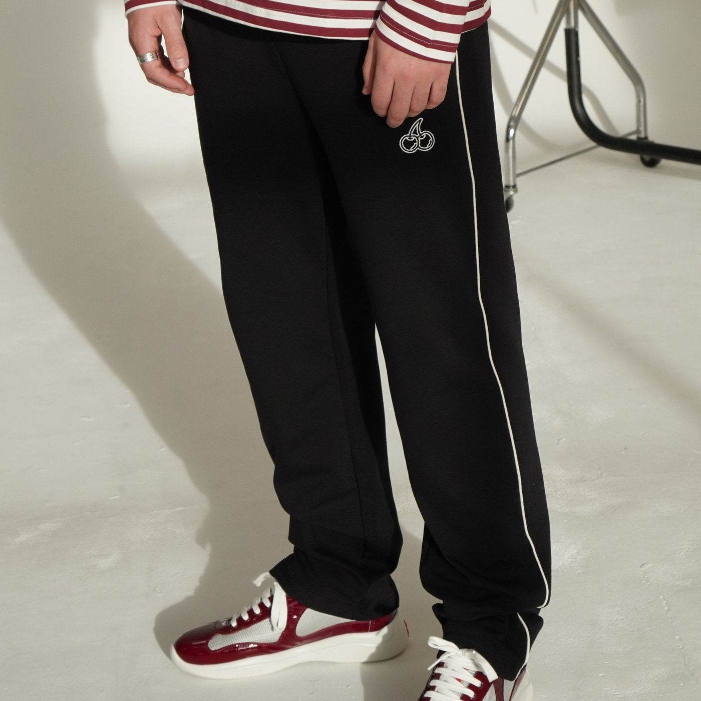 Cherry Location black tracksuit bottoms with white side stripe and cherry logo embroidery