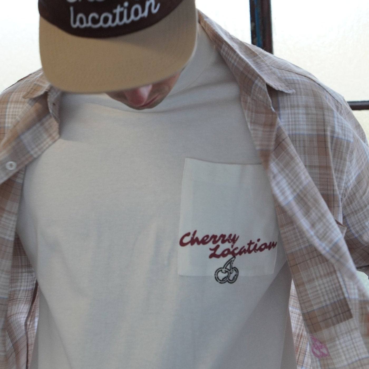 man wearing Cherry Location white t-shirt with embroidered logo and plaid shirt over it