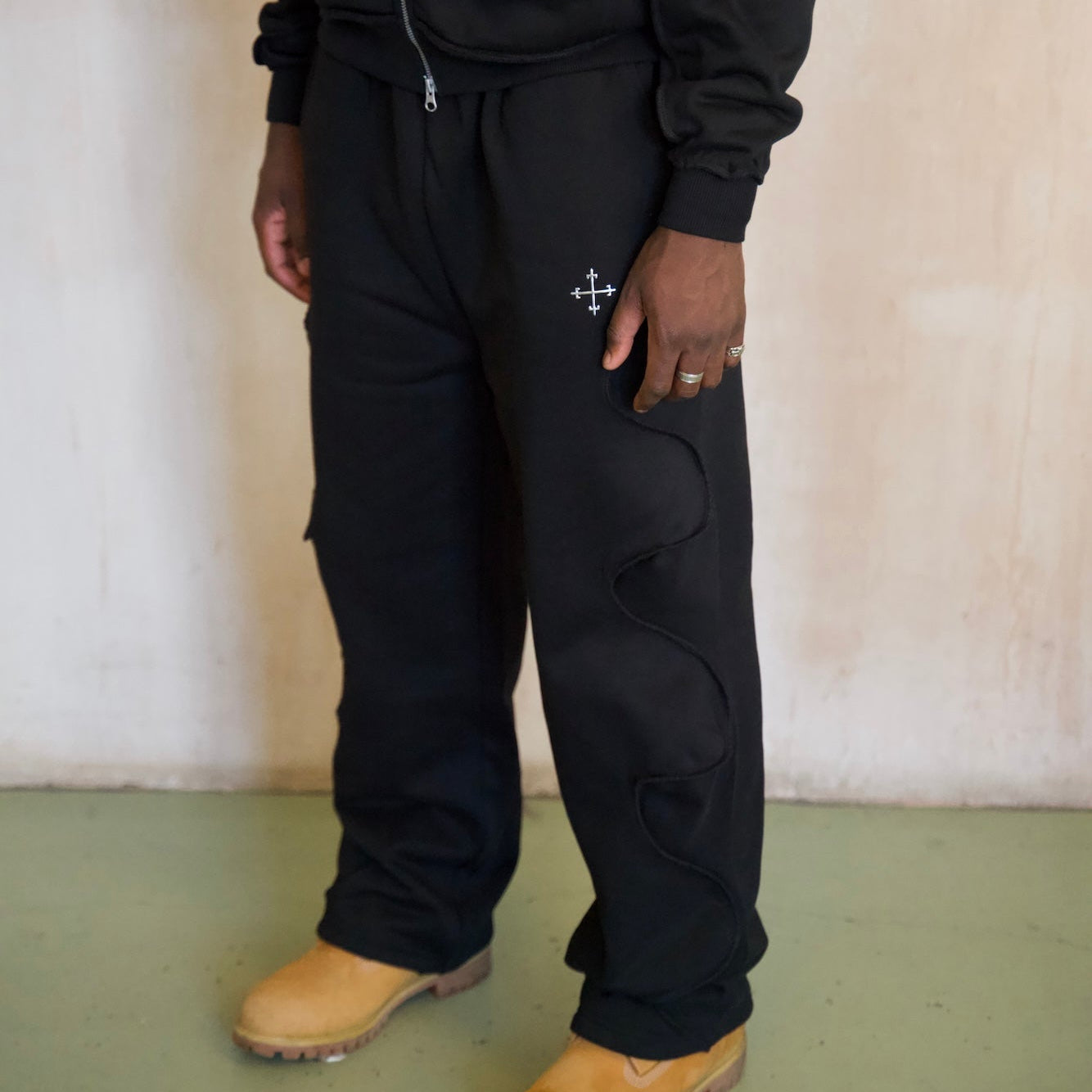 Black Saint Mind Wavy baggy sweatpants with metallic logo, ribbed waistband, side and back pockets, hidden ankle toggles, and reversed seam effect