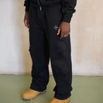 Black Saint Mind Wavy baggy sweatpants with metallic logo, ribbed waistband, side and back pockets, hidden ankle toggles, and reversed seam effect