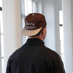 Brown Cherry Location cap worn from the back with white lettering and beige brim