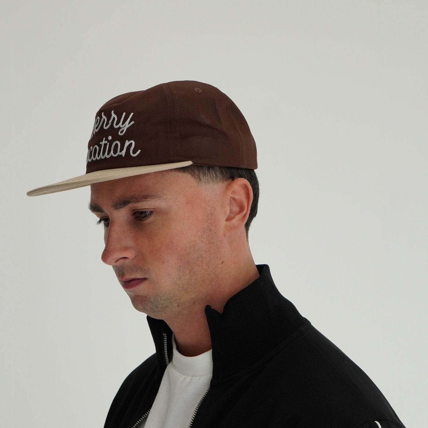 Man wearing Cherry Location brown cap with embroidery on front