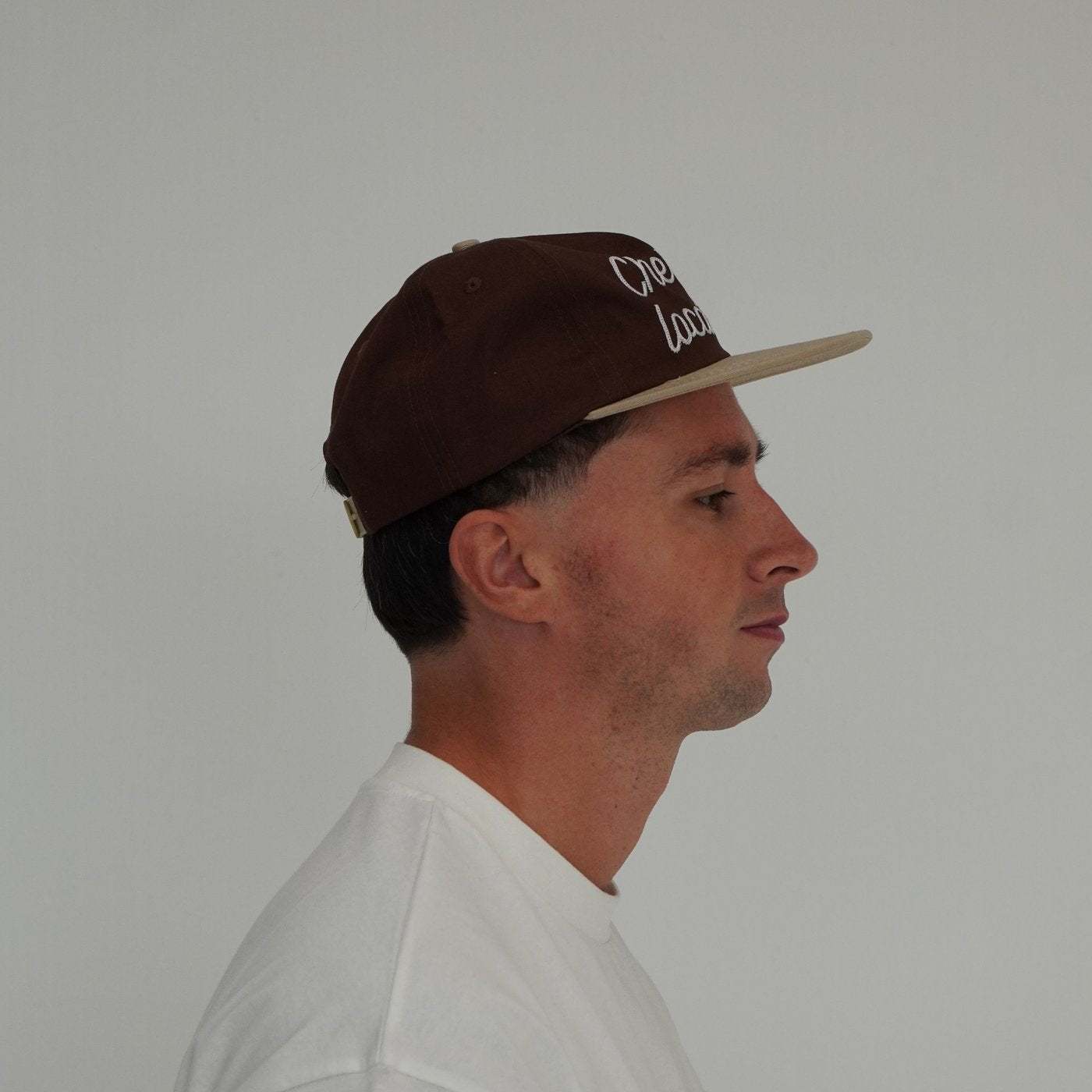 Cherry Location brown cap worn by man in white shirt side view