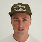 Man wearing cherry location green cap with embroidered text
