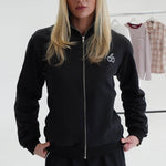 Woman wearing Cherry Location black tracksuit with front zipper and cherry logo on chest