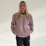Woman wearing Cherry Location OG Stripe T-Shirt with maroon and white stripes and black pants against plain background