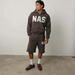 Man wearing brown Natural Art Studio NAS appliqué cotton shorts with elastic waistband and relaxed fit