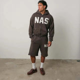 Man wearing brown Natural Art Studio NAS appliqué cotton shorts with elastic waistband and relaxed fit