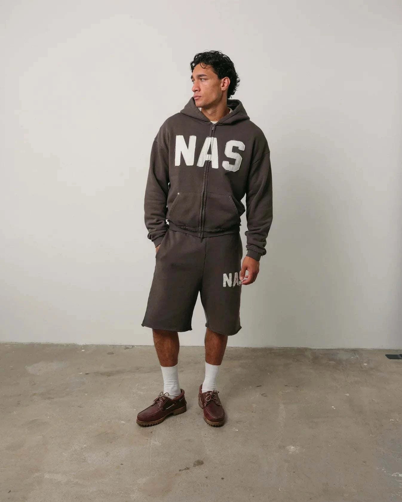 Man wearing brown Natural Art Studio NAS appliqué cotton shorts with elastic waistband and relaxed fit