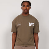 Model wearing Natural Art Studio NAS Appliqué Tee with distressed front logo and back screen print in medium size.