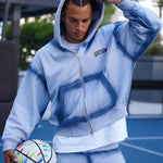 Last Lesson blue sprayed hoodie worn by a model holding a soccer ball.
