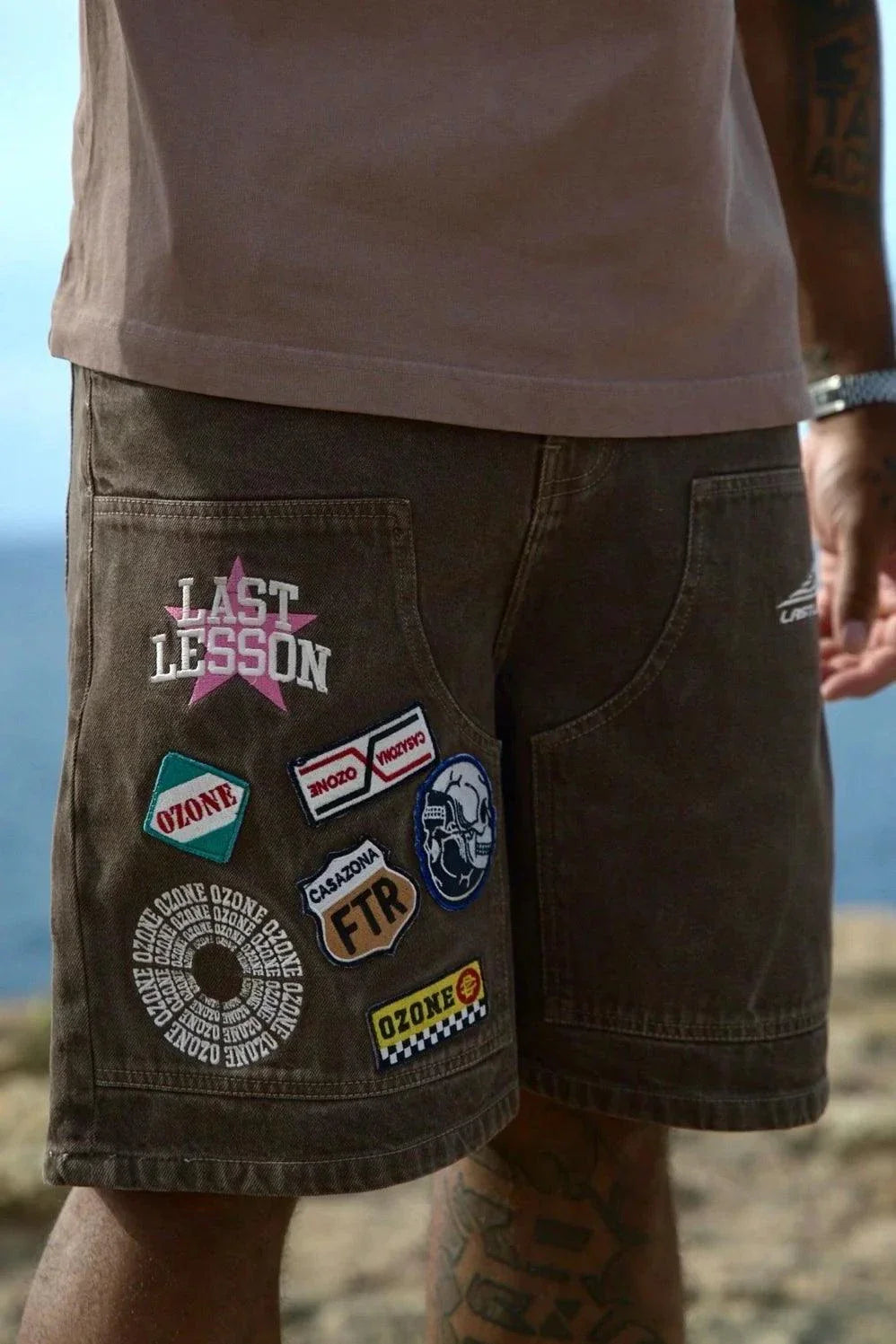 Last Lesson Badged Casazøna Shorts with colorful patches and logos on brown fabric