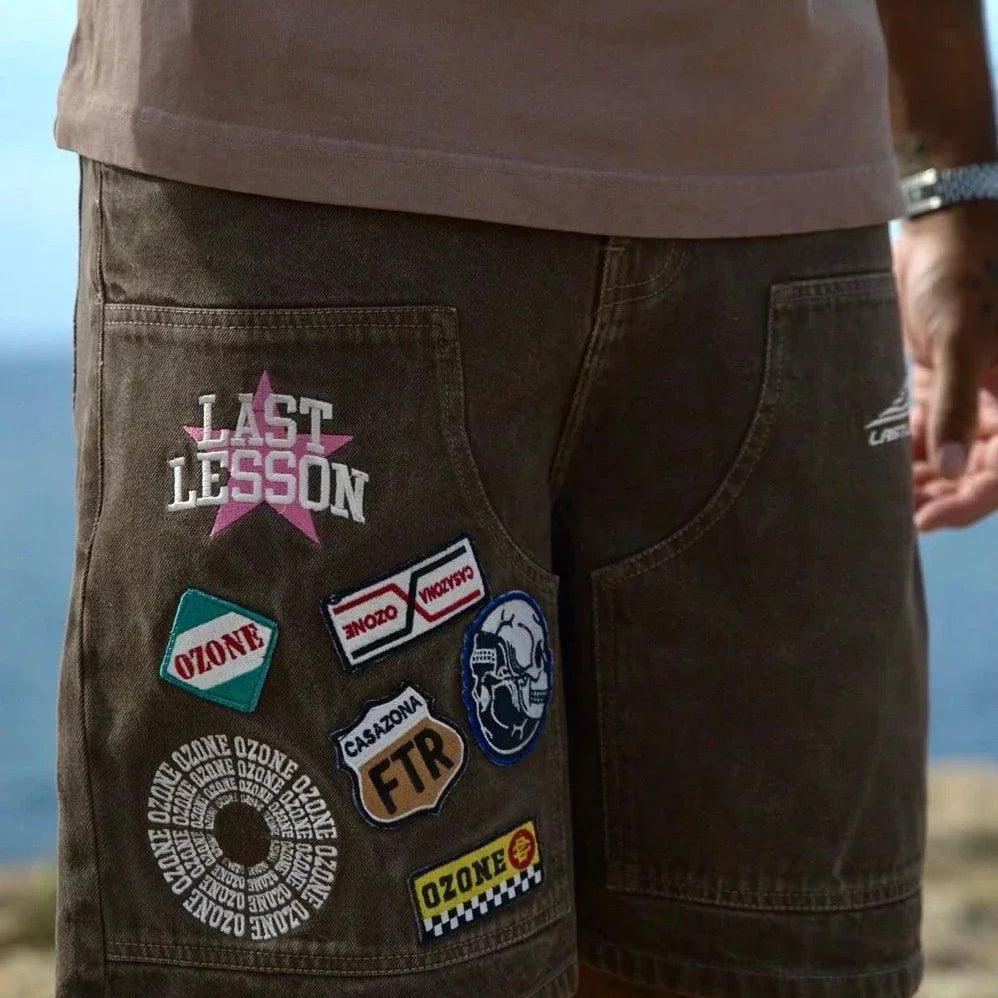 Last Lesson Badged Casazøna Shorts with colorful patches and logos on brown fabric