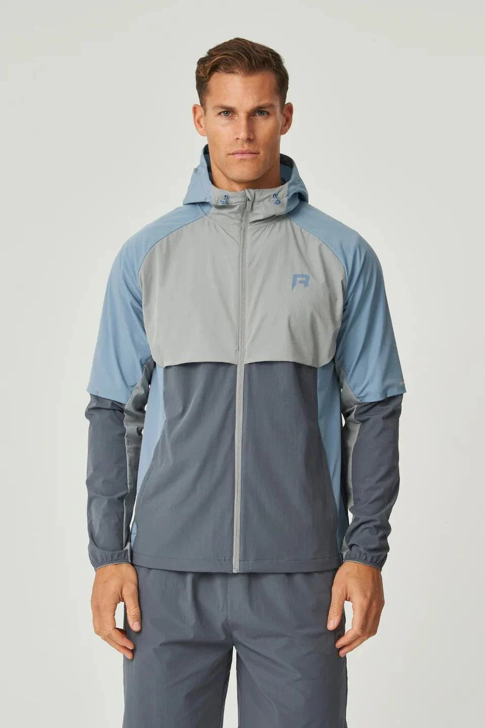 Reprimo Vortex Windbreaker in dusky blue with ergonomic design and reflective details, lightweight and wind-resistant jacket for active wear