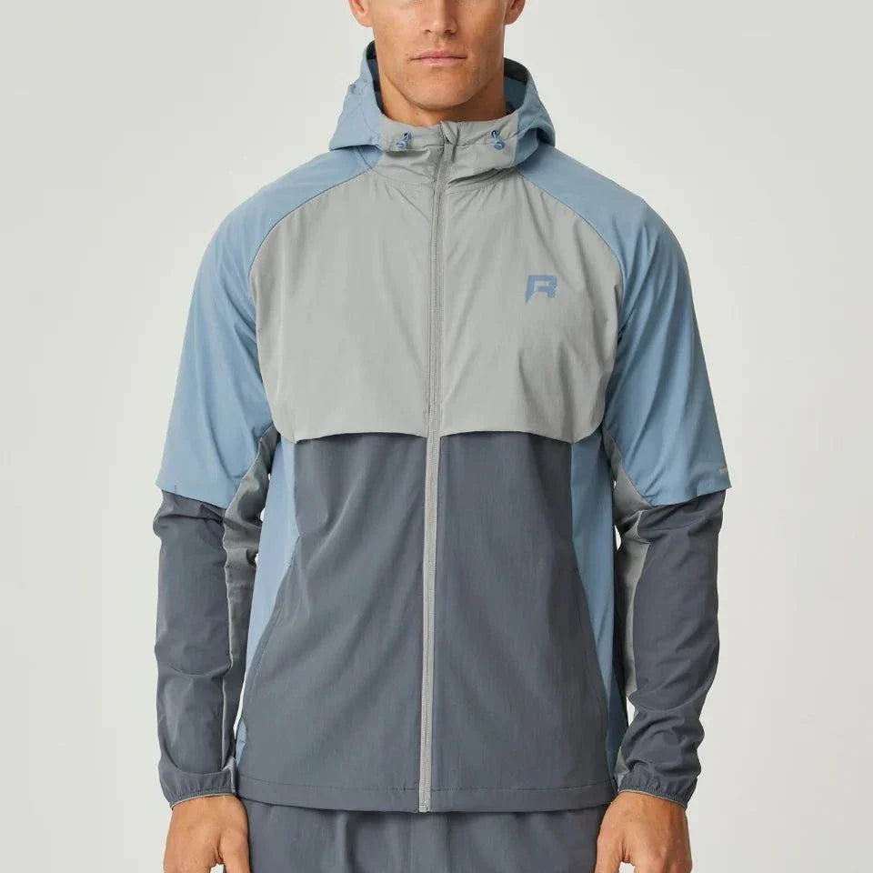 Reprimo Vortex Windbreaker in dusky blue with ergonomic design and reflective details, lightweight and wind-resistant jacket for active wear