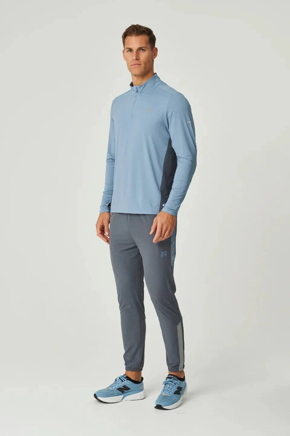 Man wearing dusky blue Reprimo Vortex Pants with ergonomic paneling and adjustable waistband.