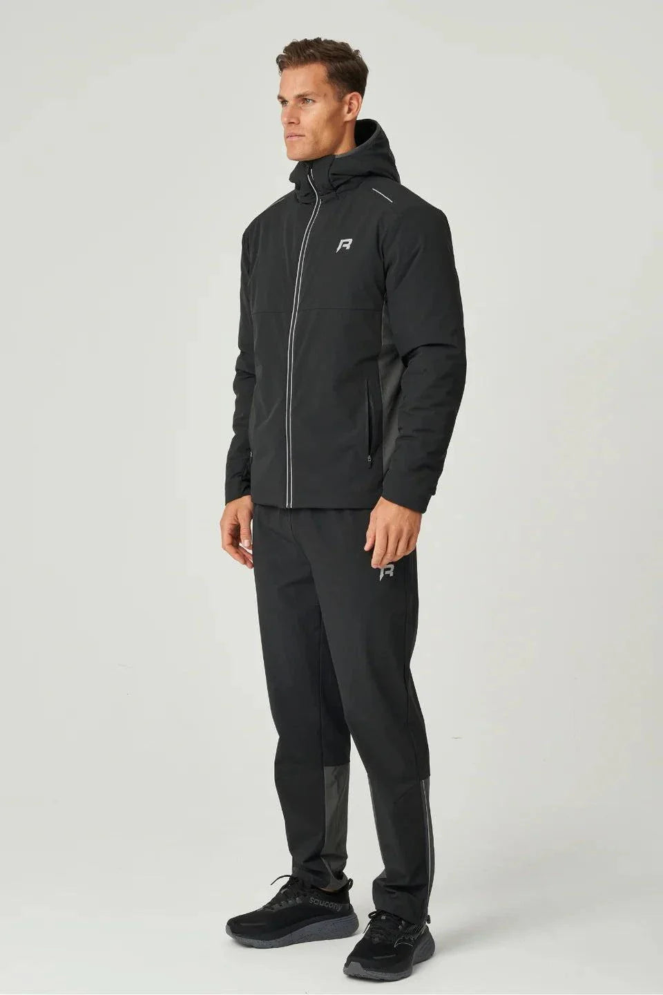 Man wearing black Reprimo Clima Jacket with zip pockets and hood, paired with matching pants