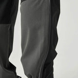 Close-up of Reprimo Clima Pants in black and charcoal showing breathable calf fabric and adjustable ankle cuffs for active performance.