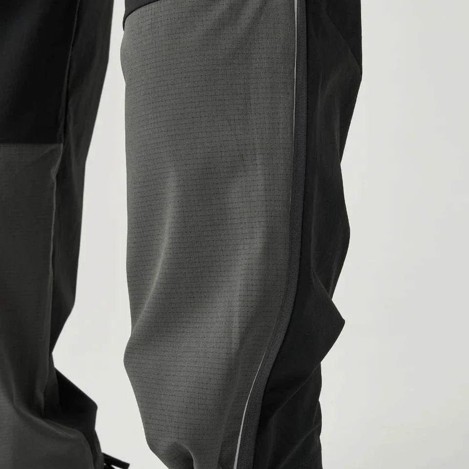 Close-up of Reprimo Clima Pants in black and charcoal showing breathable calf fabric and adjustable ankle cuffs for active performance.