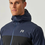 Man wearing black and navy Reprimo Nova Jacket with hood and reflective logo