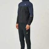 Male model wearing black and navy Reprimo Nova Pants with reflective strips and functional pockets for athletic performance and comfort