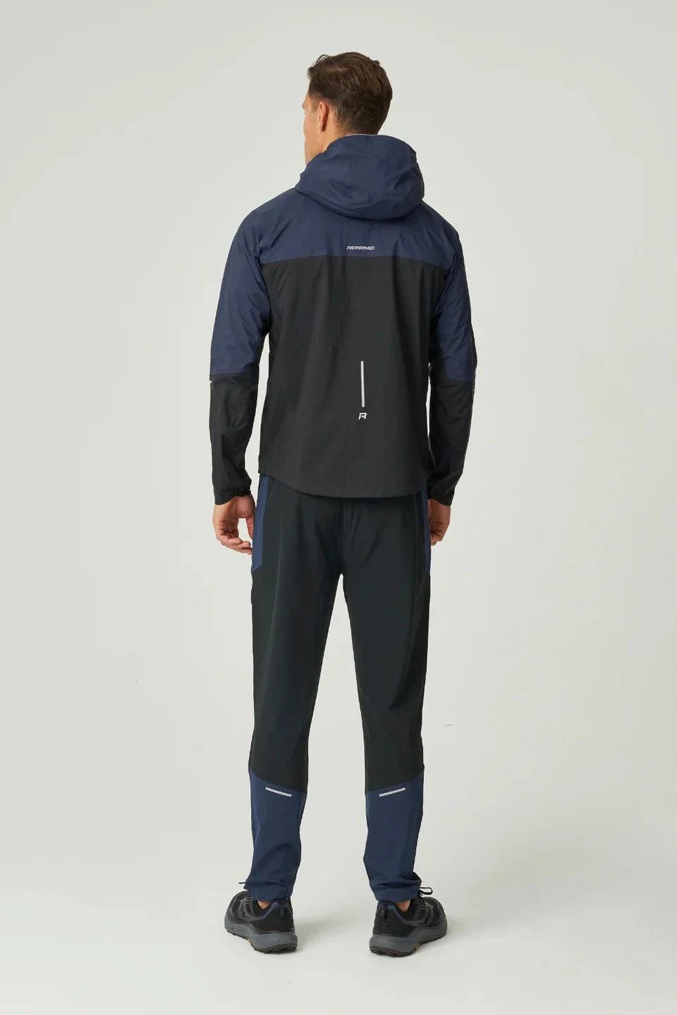Man wearing black and navy Reprimo Nova Pants with reflective strips and breathable fabric, back view