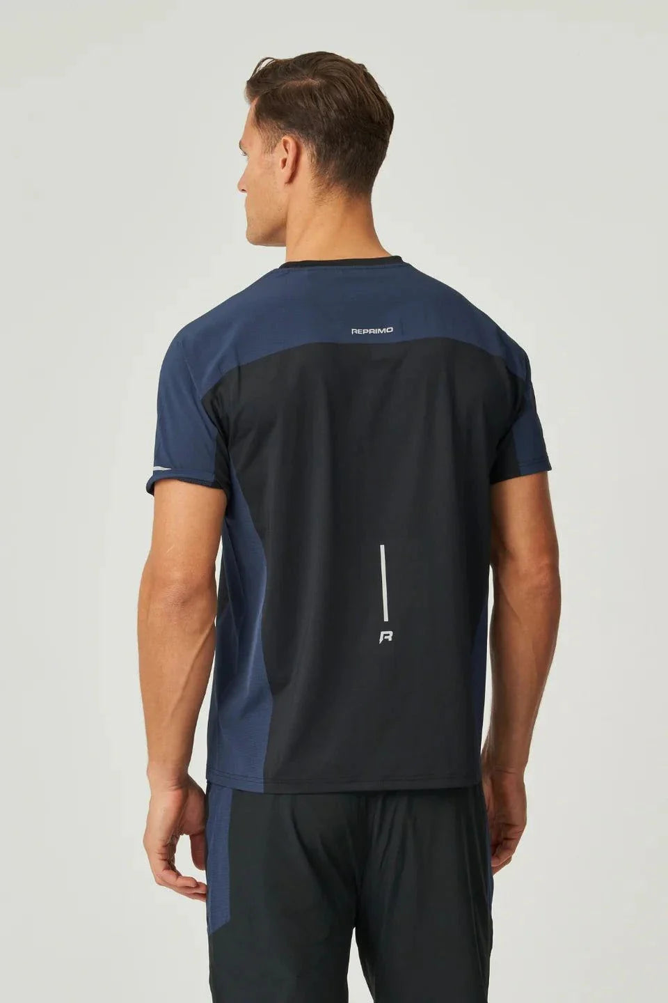 Back view of a man wearing a black and navy Reprimo Nova T-Shirt with reflective detailing and heat-sealed seams