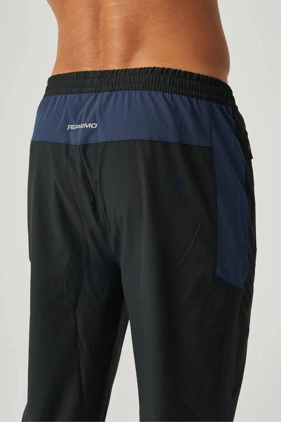 Back view of Reprimo Nova Pants in black and navy with elastic waistband and reflective logo detail